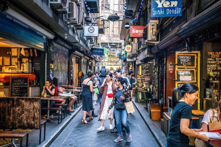 People walking down a laneway with cafes on either side